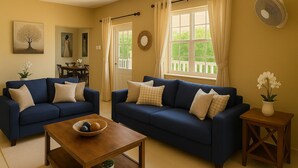 Ein Wohnzimmer mit zwei dunkelblauen Sofas, einem Holztisch als Couchtisch und einem kleinen Beistelltisch mit einem Blumentopf.