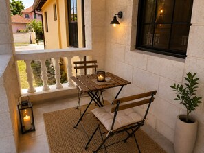 Ein Balkon mit Tisch, Stühlen, einer Laterne und einem Blumentopf.