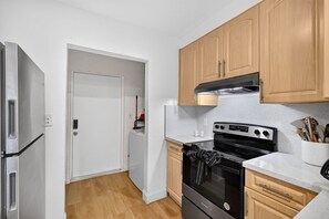 Eine kleine Küche mit Kühlschrank, Backofen und Holzschränken.