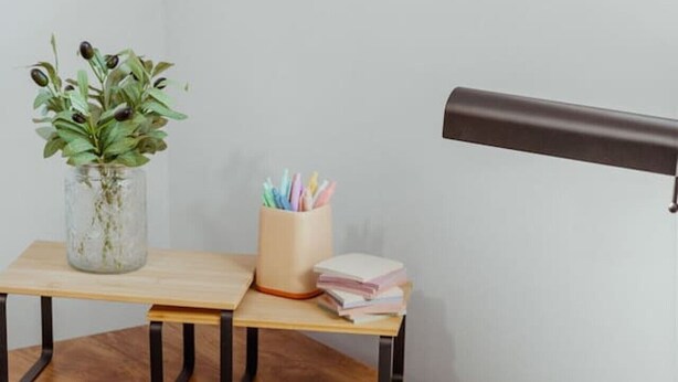 Ein Holztisch mit einem Buch, einer Lampe und einer Pflanze.