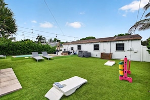 Ein Garten mit Pool, Liegestühlen und einem Spielbereich.