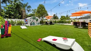 Ein gepflegter Garten mit Kunstgrasanlage, Sitzgelegenheiten im Freien und einem Spielbereich für Kinder.