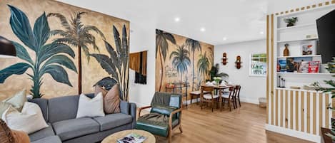 A living room with a sofa, coffee table, and a dining area with chairs and a table.