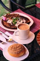 Una mesa servida con un plato de comida, una taza de café y un pastel.