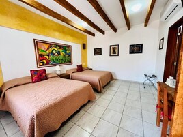 Habitación de hotel con dos camas, un cuadro grande en la pared y una mesita con una silla.