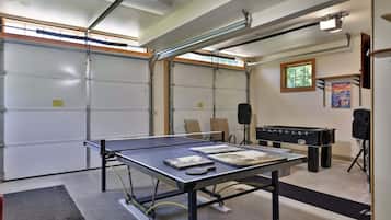 Huoneessa on pingispöytä, pöytäjalkapallopöytä ja projektori.