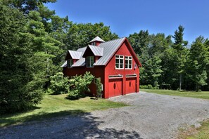 A red building with a gravel driveway and surrounded by trees.