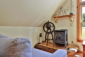 Une pièce chaleureuse avec un plancher en bois, un canapé, une cheminée et une fenêtre donnant sur un paysage verdoyant.