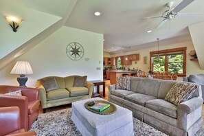 A spacious living area with a high ceiling, a dining area, and a kitchen with wooden cabinets.