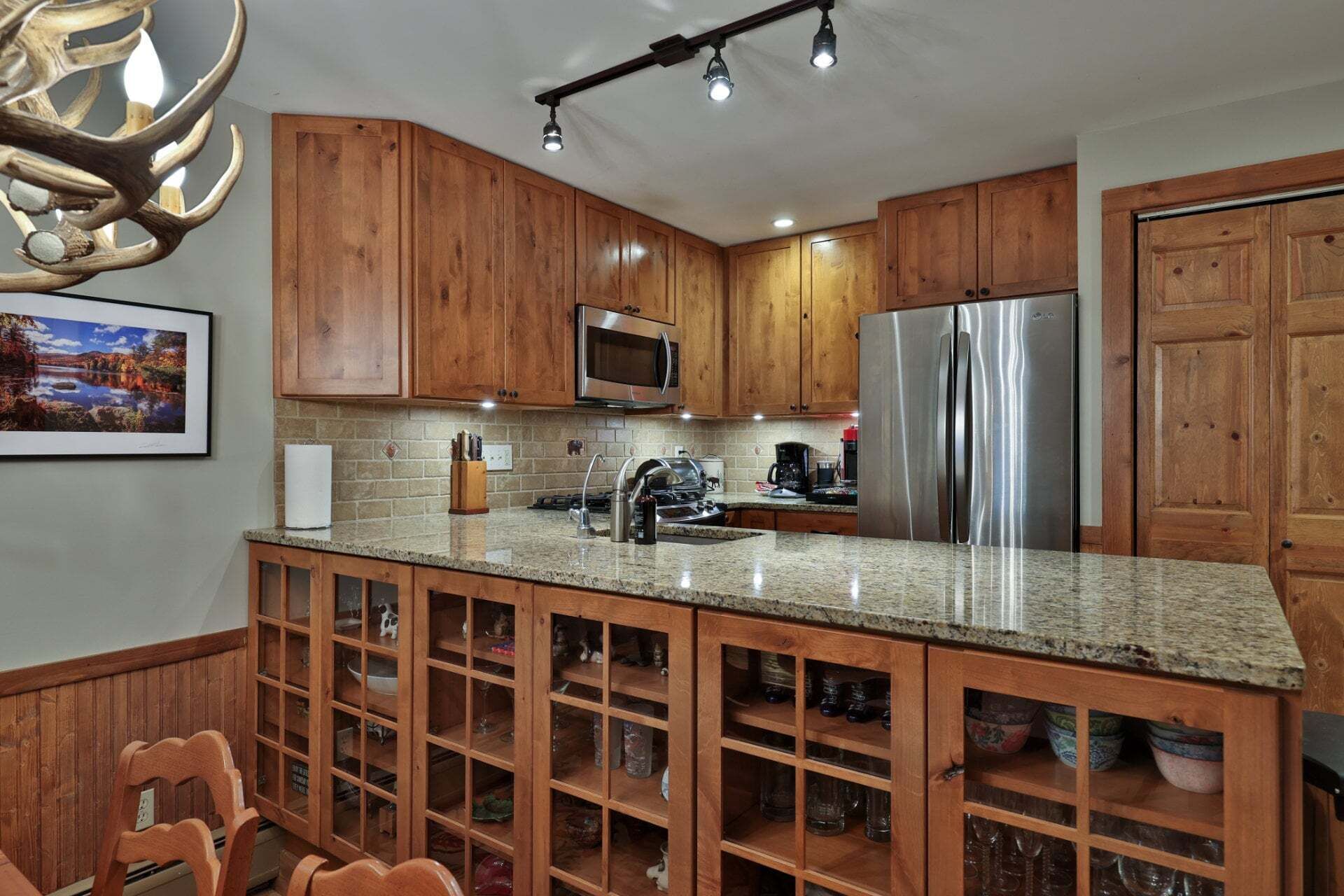 A kitchen with wooden cabinets, a stainless steel refrigerator, a microwave, and a granite countertop.
