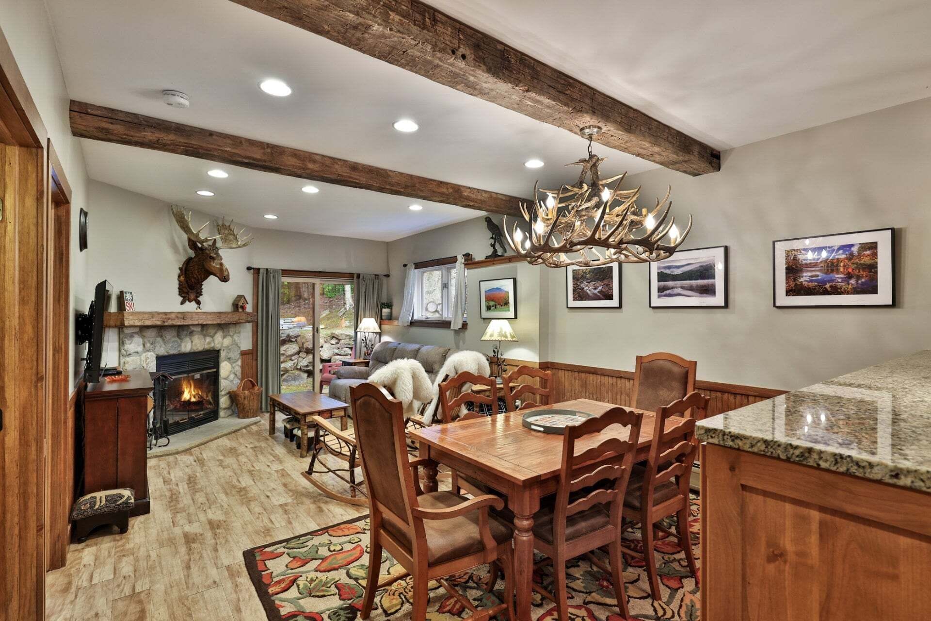 A dining area with a wooden table and chairs, a fireplace, and a chandelier.