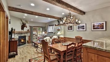 A dining area with a wooden table and chairs, a fireplace, and a chandelier.