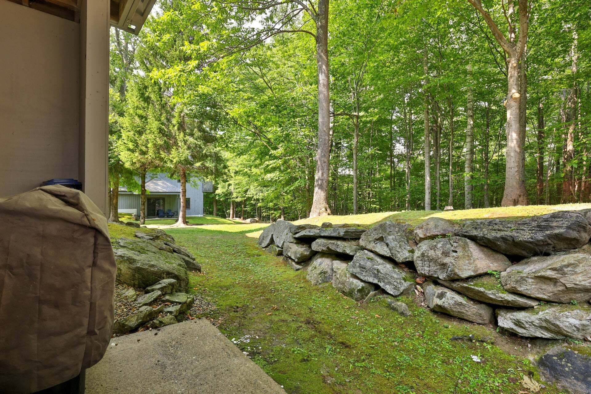 A stone wall and a building with a covered outdoor area, surrounded by a forest.
