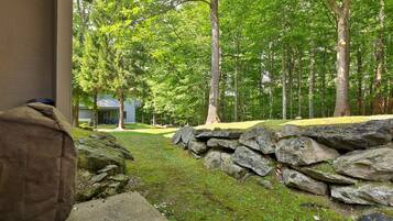 A stone wall and a building with a covered outdoor area, surrounded by a forest.