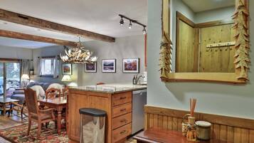 A kitchen with a wooden island, a chandelier, and a large mirror with a wooden frame.