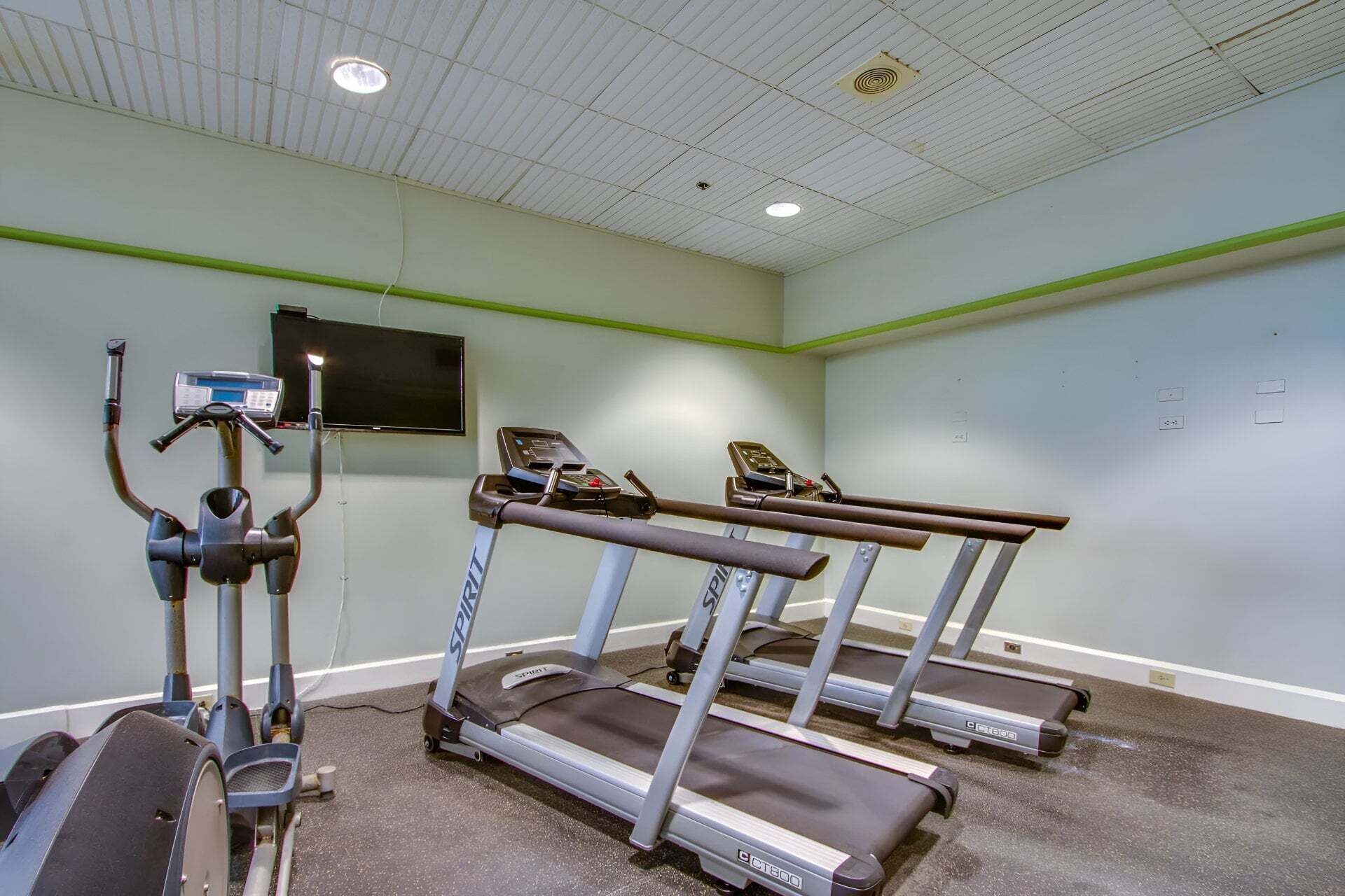 A gym with treadmills, a stationary bike, and a rowing machine.