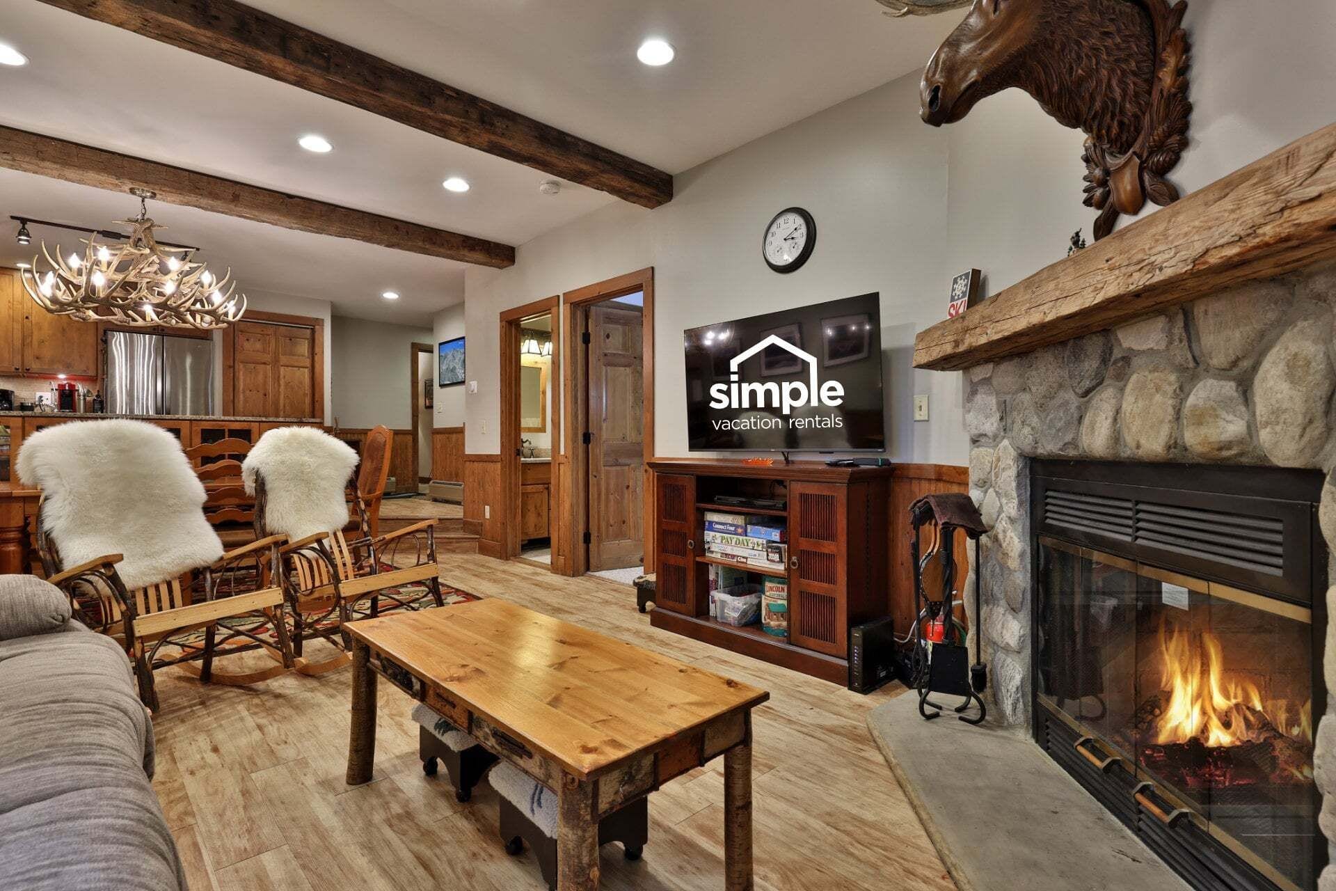 A rustic interior with a fireplace, wooden furniture, and a television displaying 'simple vacation rentals'.