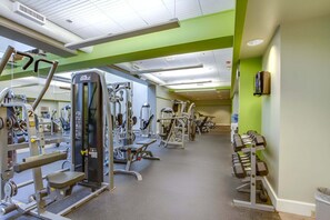 Uma academia com diversos equipamentos de exercícios, incluindo aparelhos de musculação e pesos livres.