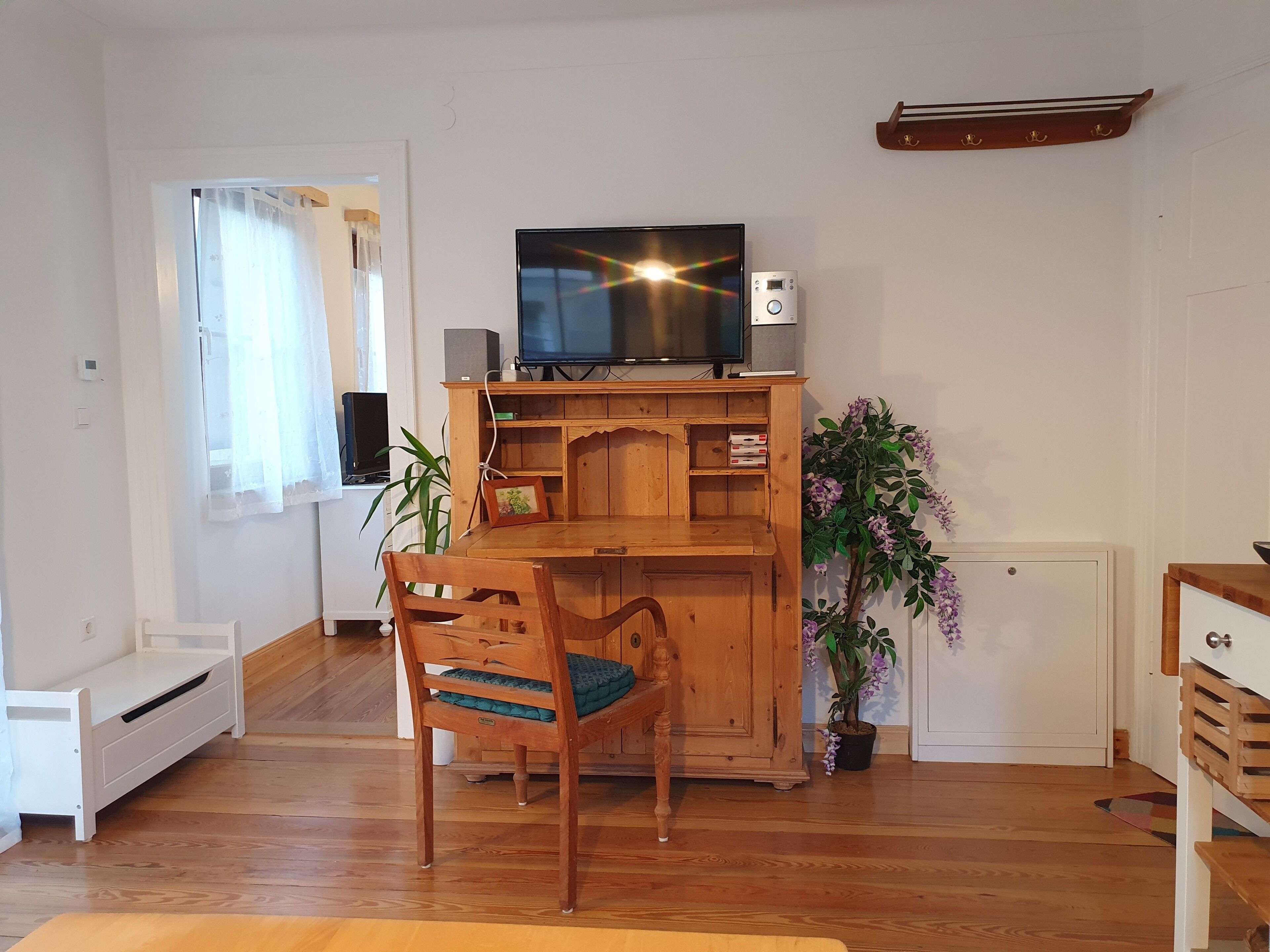 A living room with a wooden entertainment unit, a television, a plant, and a chair.