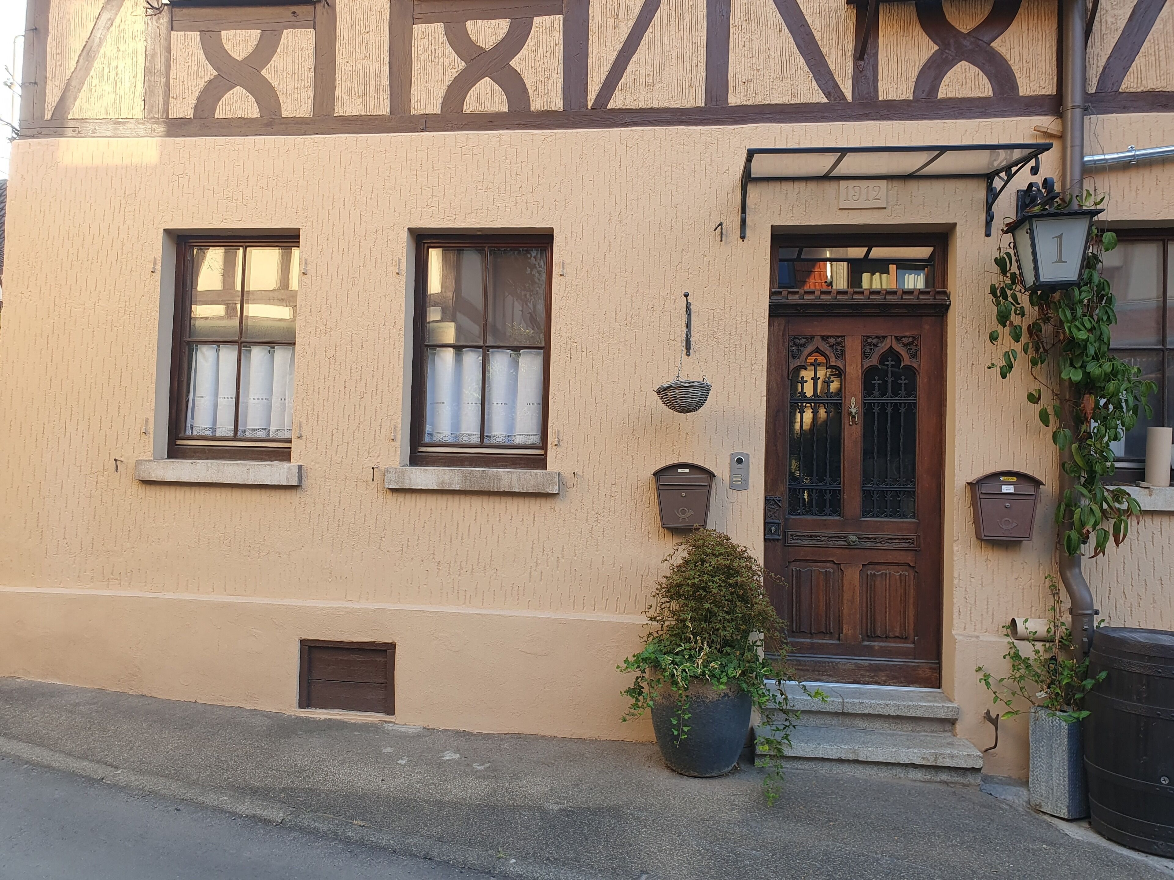 Ein Gebäude mit traditioneller Fassade, einer Holztür mit Fensterglas und einem Blumentopf davor.