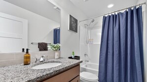 A bathroom with a white sink, a mirror, a shower, and a blue shower curtain. - Proper Stay 2BD/2BA  Stanfield (Stanfield)