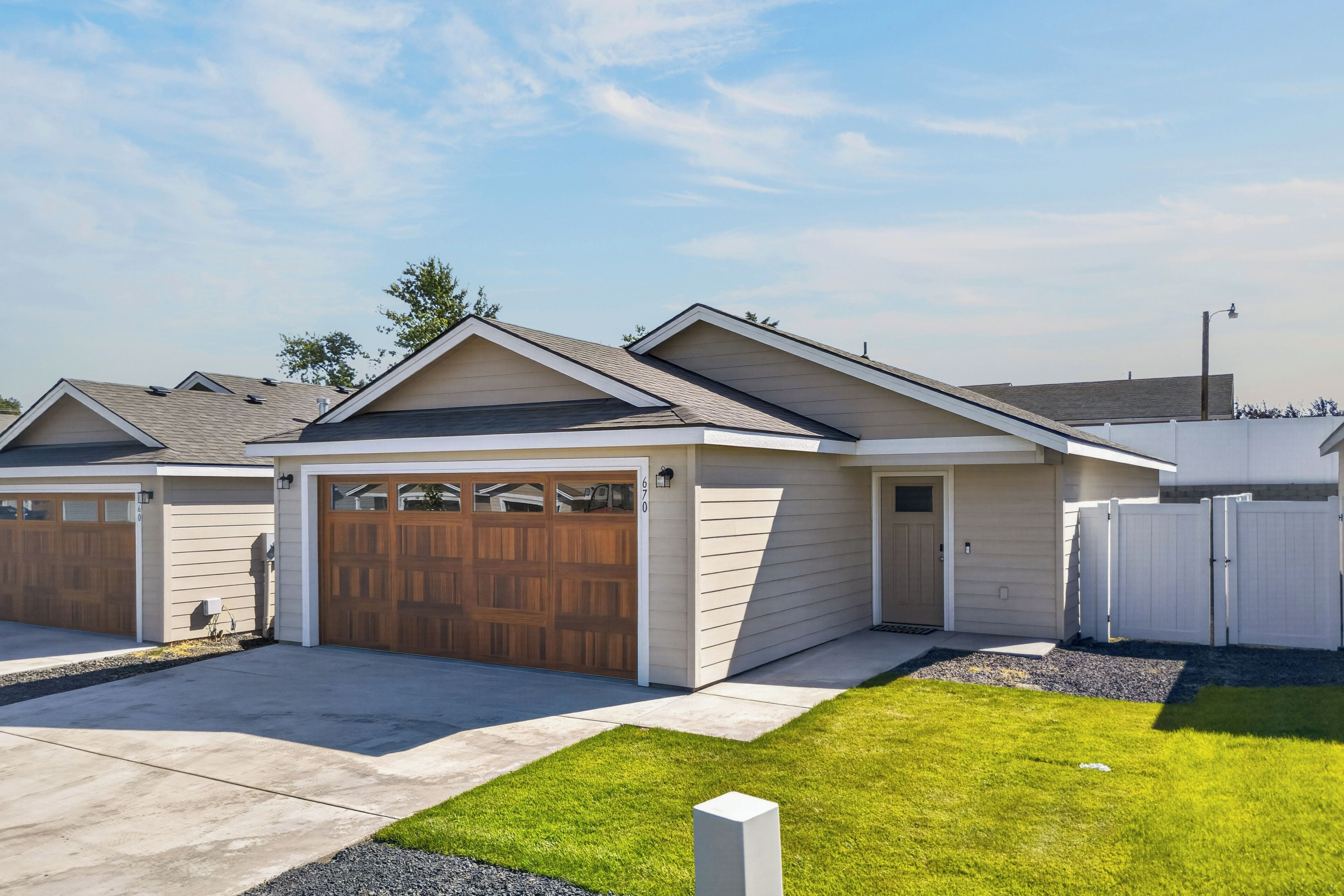 A residential building with a garage, a covered driveway, and a well-maintained lawn.
