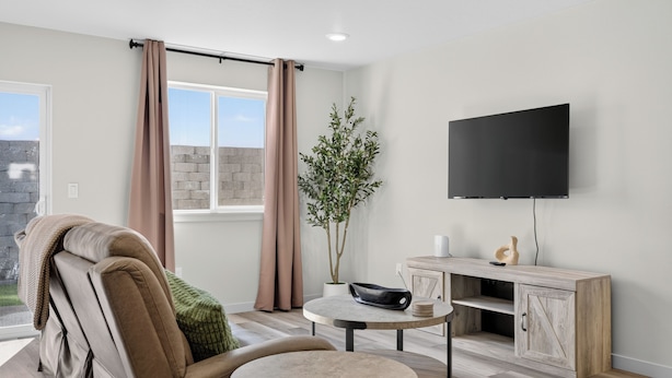 A modern living room with a sofa, a small round table, a flat-screen TV mounted on the wall, and a potted plant. - Proper Stay 2BD/2BA  Stanfield (Stanfield)
