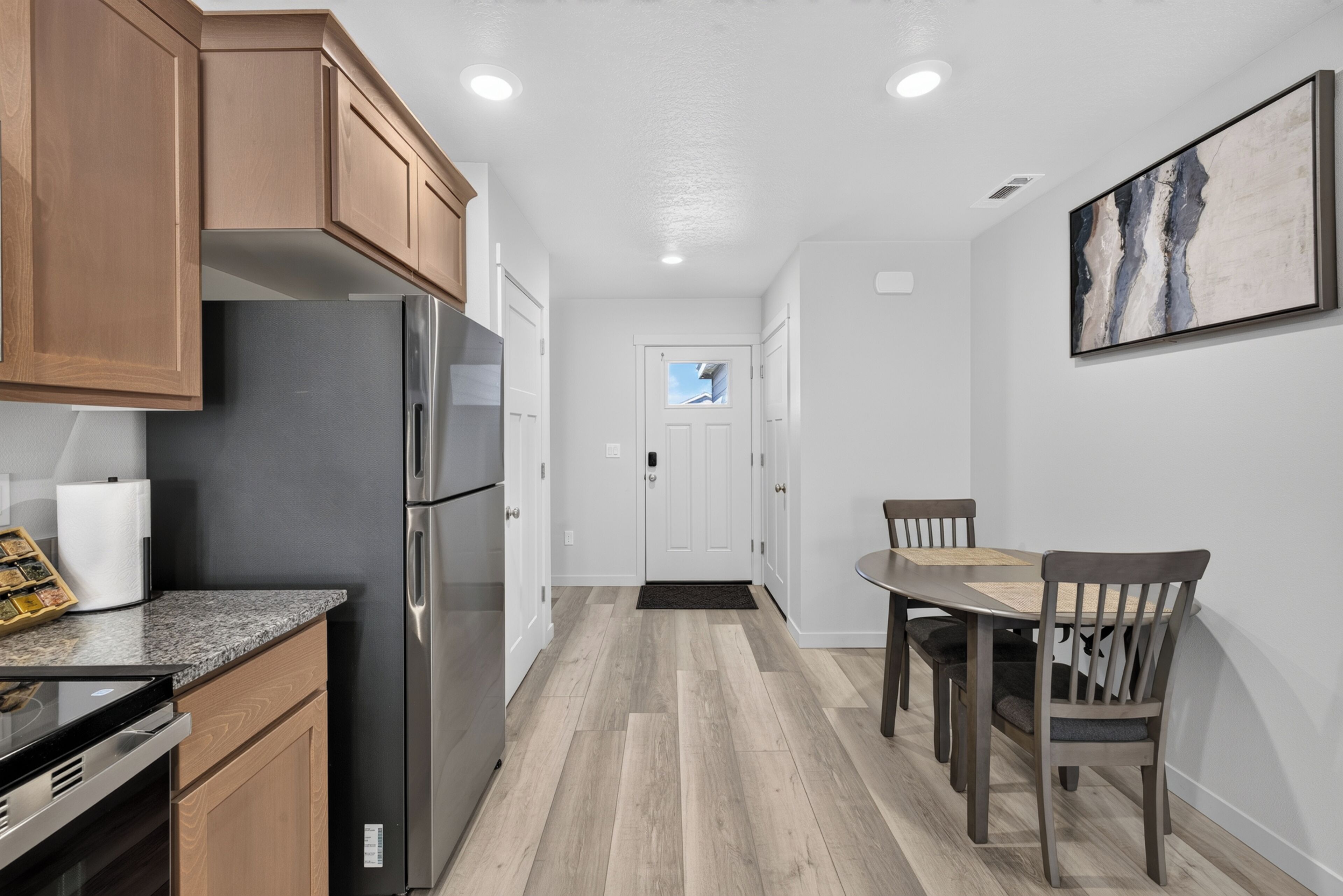 A modern kitchen with wooden cabinets, stainless steel appliances, and a dining area with a table and chairs.