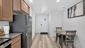 A modern kitchen with wooden cabinets, stainless steel appliances, and a dining area with a table and chairs.