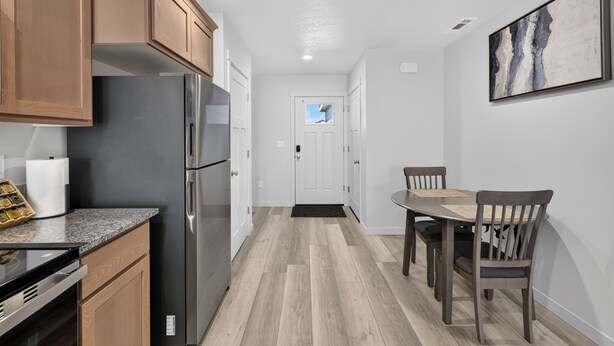 Une cuisine moderne avec des meubles en bois, des appareils en acier inoxydable et un coin repas comprenant une table et des chaises.