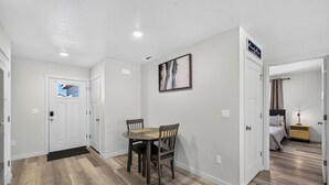 A hotel room with a wooden floor, a dining table with chairs, a bed, and a nightstand with a lamp. - Proper Stay 2BD/2BA  Stanfield (Stanfield)