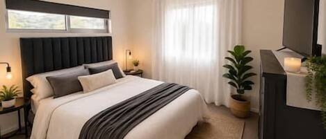 A bedroom with a bed, bedside tables, a ceiling fan, a TV, and a window with curtains.