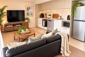 Ein modernes Wohnzimmer mit einer Couch, einem Couchtisch und einem Flachbildfernseher.