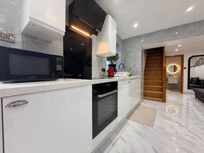 Eine moderne Küche mit Mikrowelle, Backofen und Kaffeemaschine auf der Arbeitsplatte.