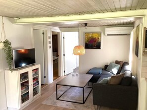 A living room with a television, sofa, coffee table, and a hanging lamp.