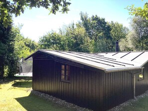 A wooden shed with a sloped roof, surrounded by a grassy yard and trees. - 6 Person Holiday Home in Ansager (Ansager)