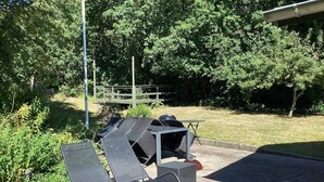 Buiten zitgedeelte met een barbecue, omringd door groen.