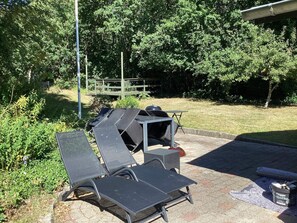 Sitzgelegenheiten im Freien mit Grill, umgeben von viel Grün.