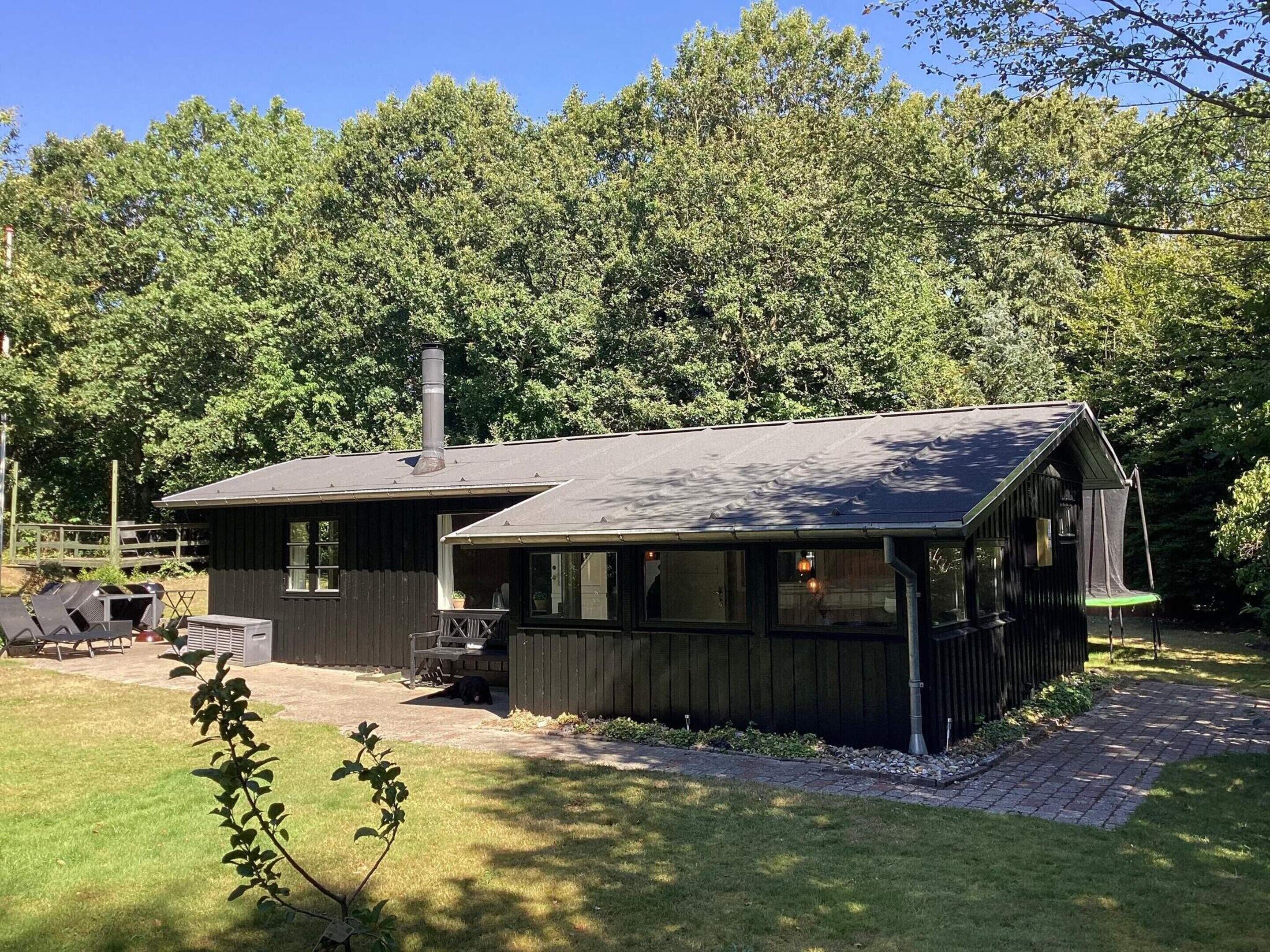 Une cabane avec une cheminée, une terrasse et une allée pavée.
