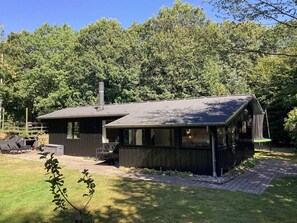 A cabin with a chimney, a deck, and a paved driveway.