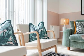 Ein modernes Wohnzimmer mit einer Couch, einem Sessel und einer Lampe.