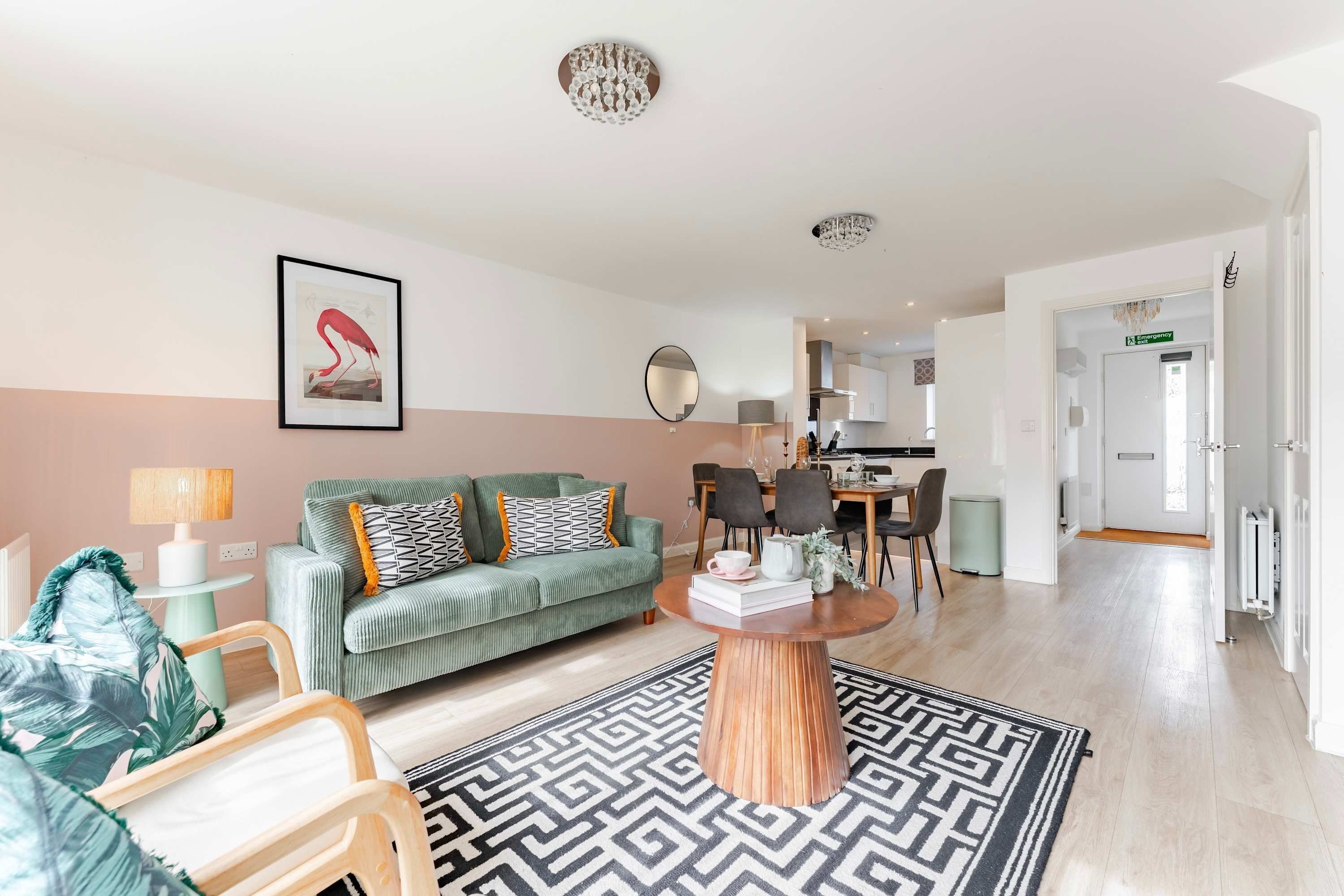 A modern living room with a sofa, coffee table, and a dining area with chairs and a table.