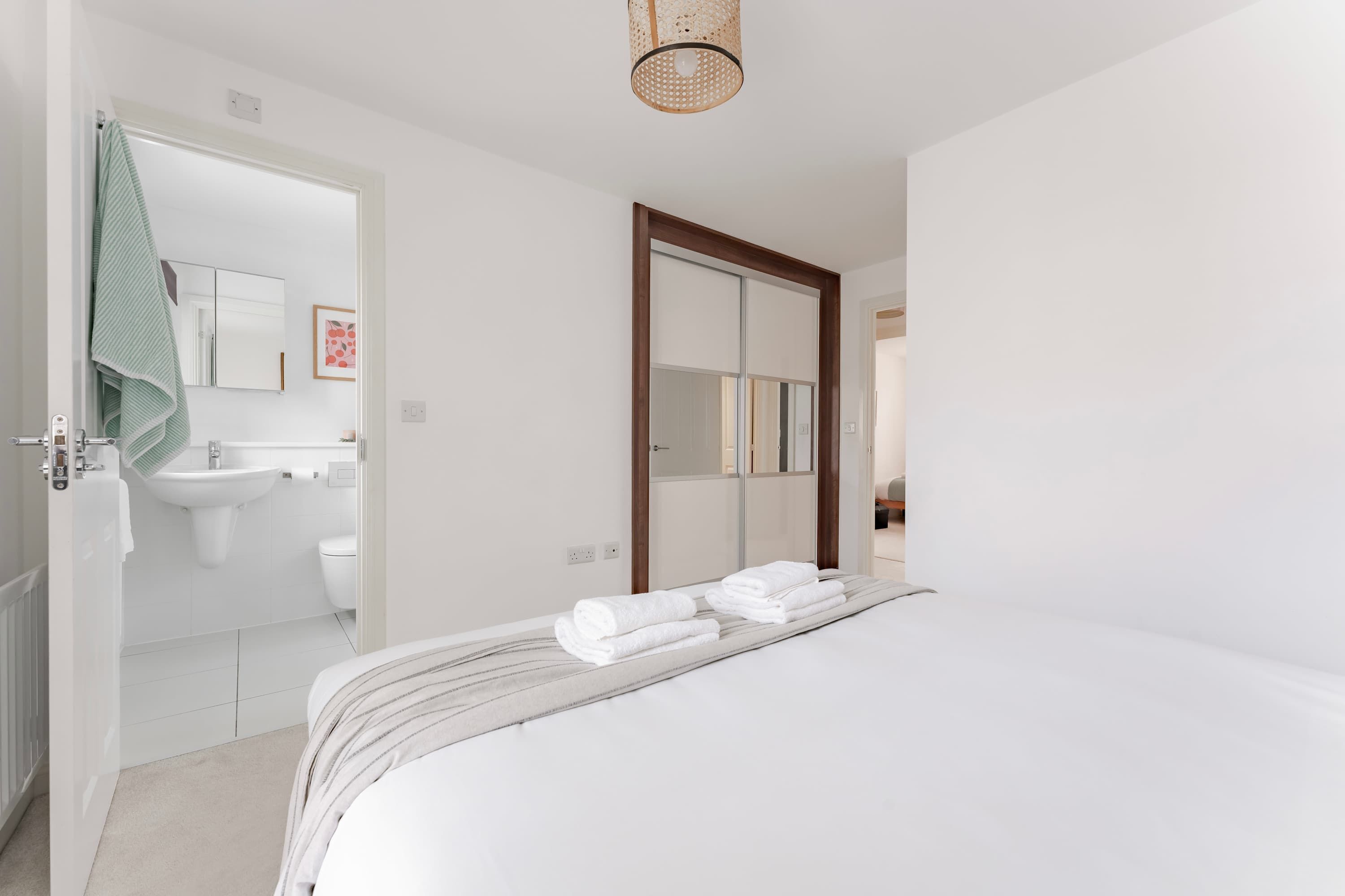 Een hotelkamer met een bed, een badkamer met wastafel en toilet, en een spiegel.