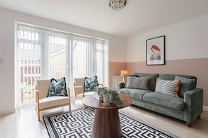 Ein Wohnzimmer mit Sofa, Sesseln, einem Couchtisch und einem Bild an der Wand.