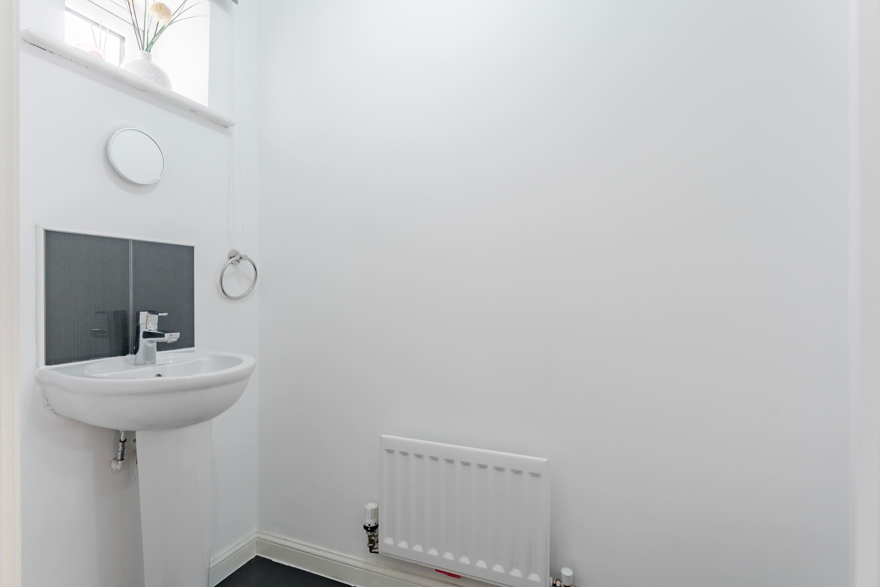 Ein Badezimmer mit Waschbecken, Spiegel und Heizkörper.