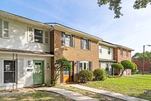 A row of townhouses with a brick facade, a green door, and a number '710' on the side. - 3BR Old Village Retreat - Extended Stay w/ Pool (Mount Pleasant)