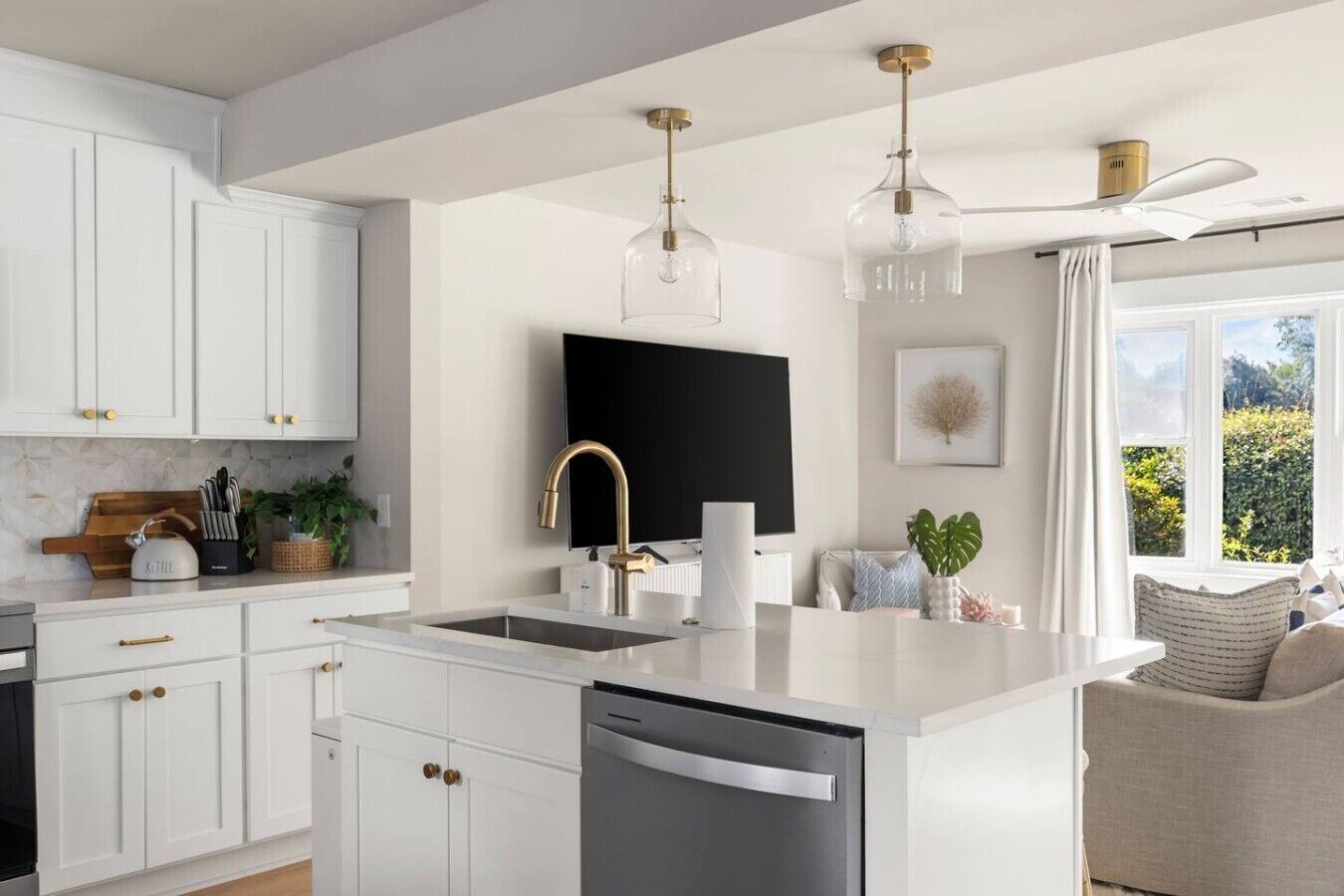A modern kitchen with white cabinetry, a central island, a built-in dishwasher, and pendant lighting.