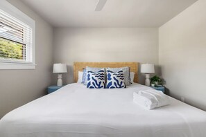 A neatly made bed with white linens, a wooden headboard, and two bedside lamps. - 3BR Old Village Retreat - Extended Stay w/ Pool (Mount Pleasant)