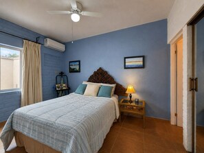 A bedroom with a bed, bedside table, lamp, air conditioning unit, and a window with curtains. - Private infinity pool & Jacuzzi 4BR Oceanfront (San Carlos)