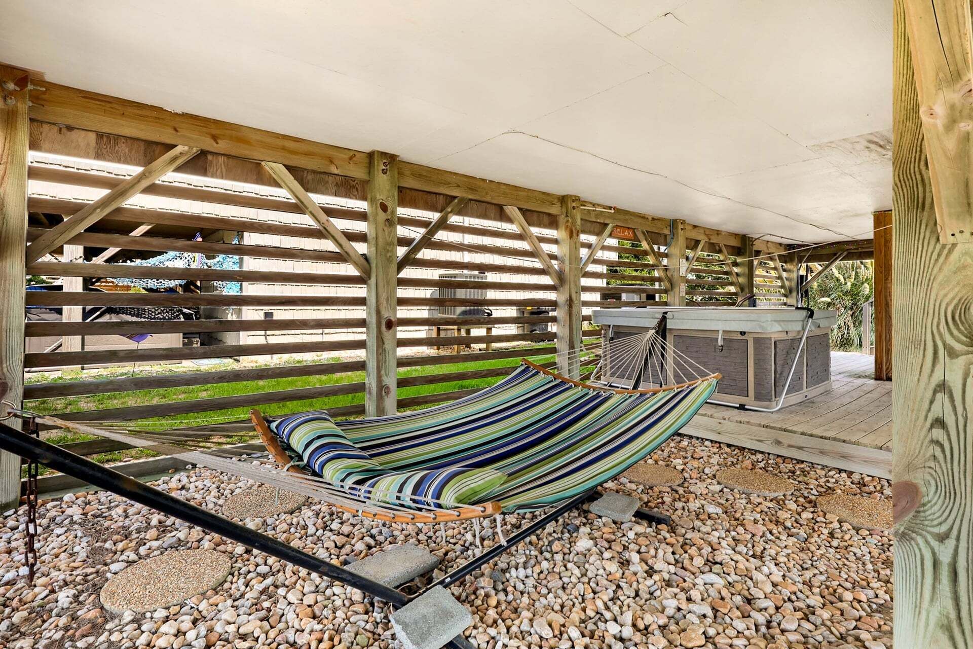 Un hamac sous une pergola en bois, avec un jacuzzi en arrière-plan.